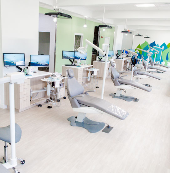 Modern pediatric dental operatory with multiple treatment stations and equipment in bright clinical setting.