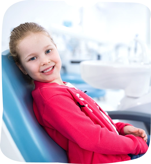 Young girl smiling in dental chair wearing pink jacket at pediatric dental office